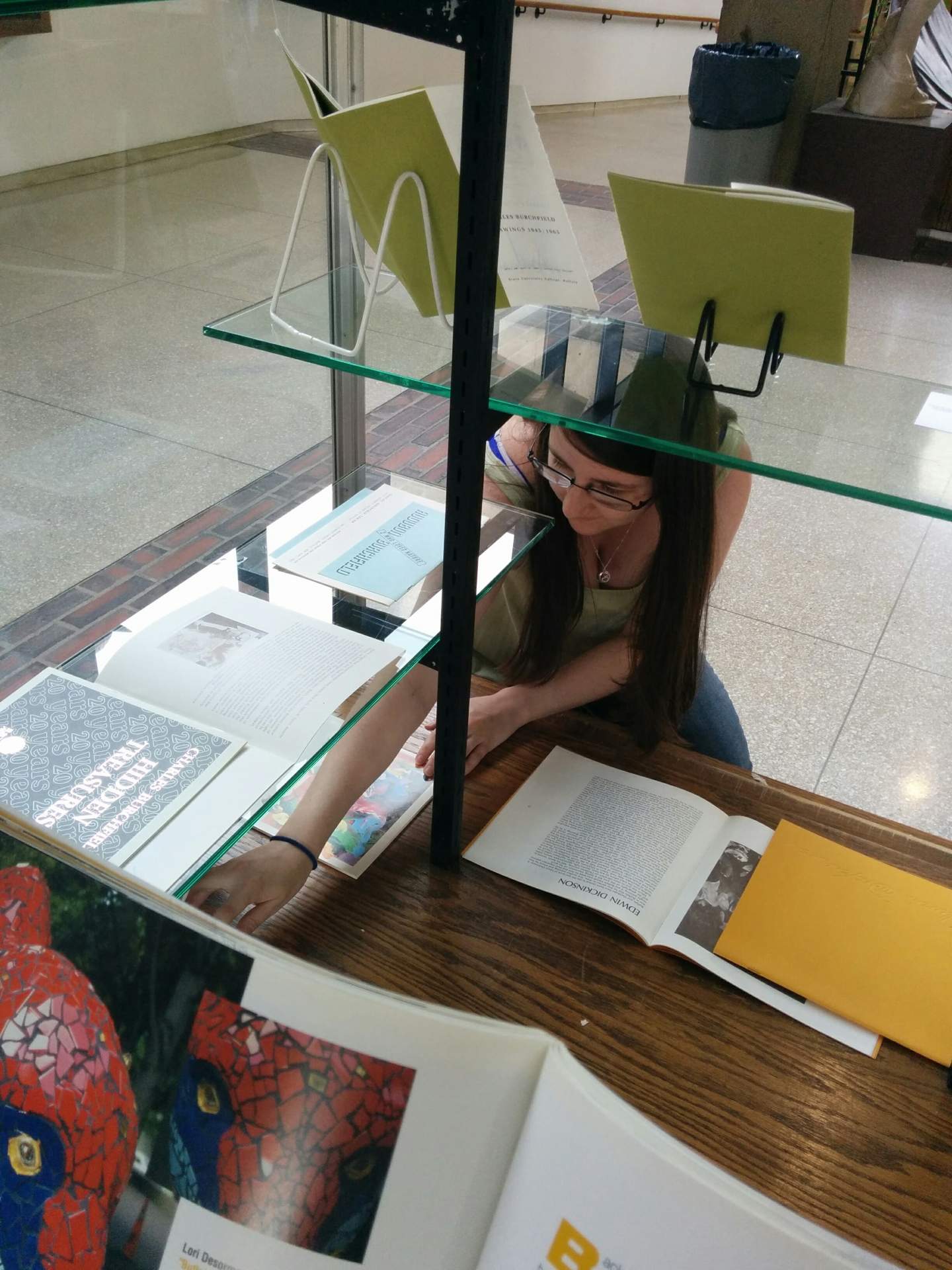 Intern Mary Langille installing Burchfield Penney Art Center publications in display cases at the E.H. Butler Library at SUNY Buffalo State