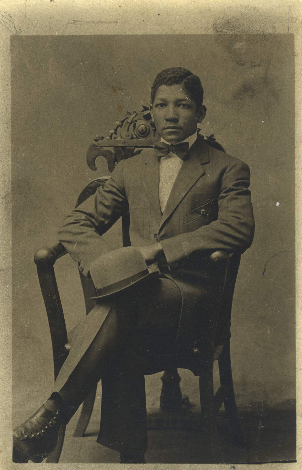 Portrait of John E. Brent seated in chair with hat