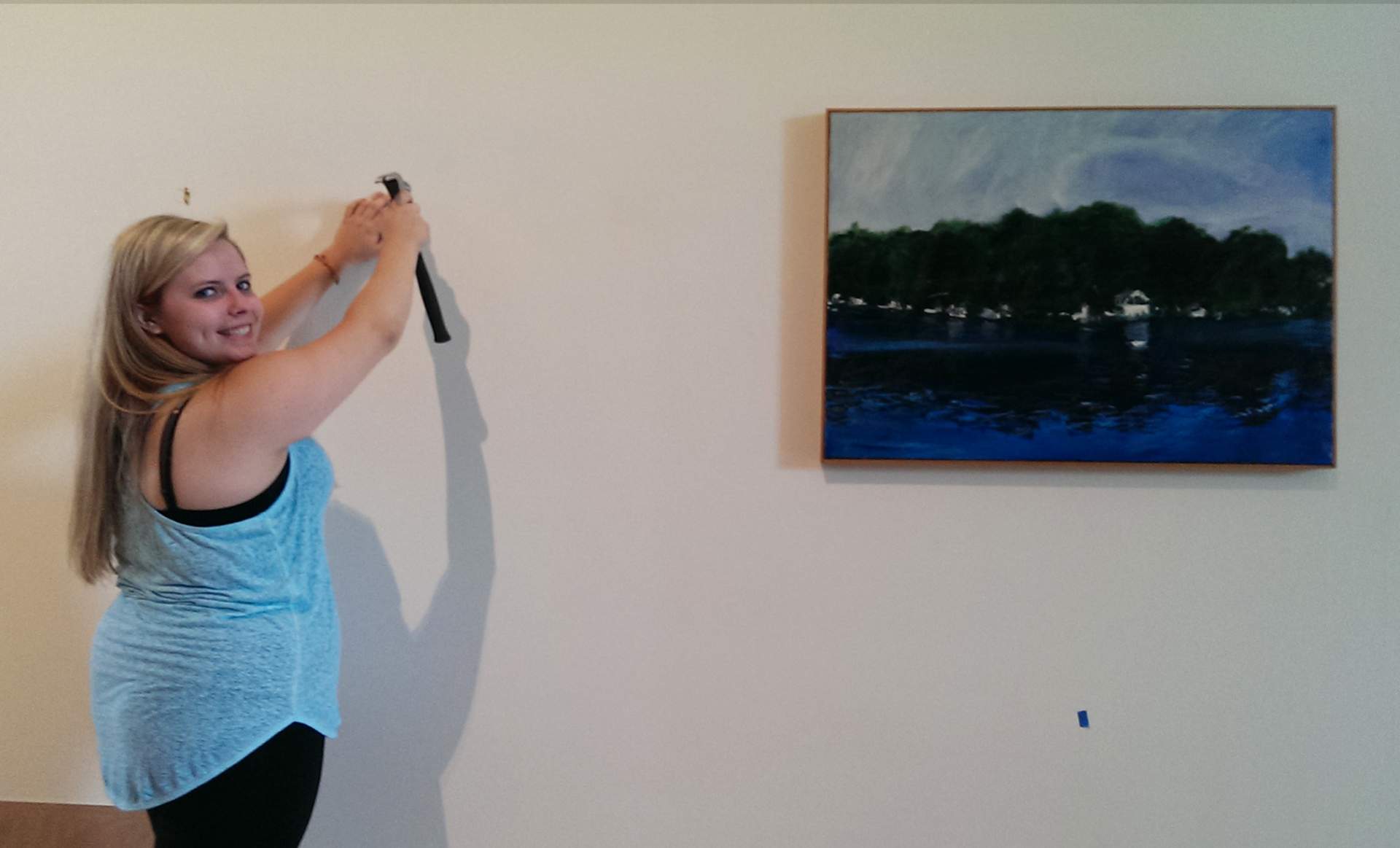 Archives Intern Danielle Gmerek hanging artwork for the Displacement: Barge Prototype opening